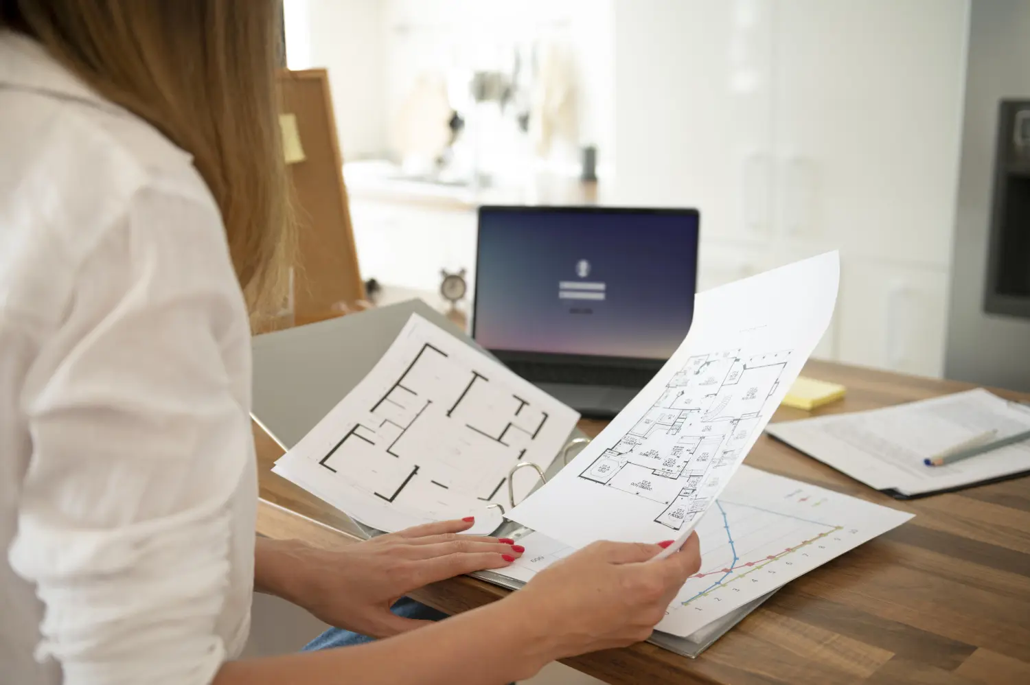 Sally Brandt Immobilien - Immobilienkonzepte - Eine Person prüft architektonische Baupläne. Dabei handelt es sich um detaillierte Pläne oder Entwürfe, die häufig im Bauwesen und Ingenieurwesen verwendet werden.
